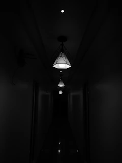 A bright hallway featuring sleek furniture pieces and a series of ceiling lamps creating a welcoming path.