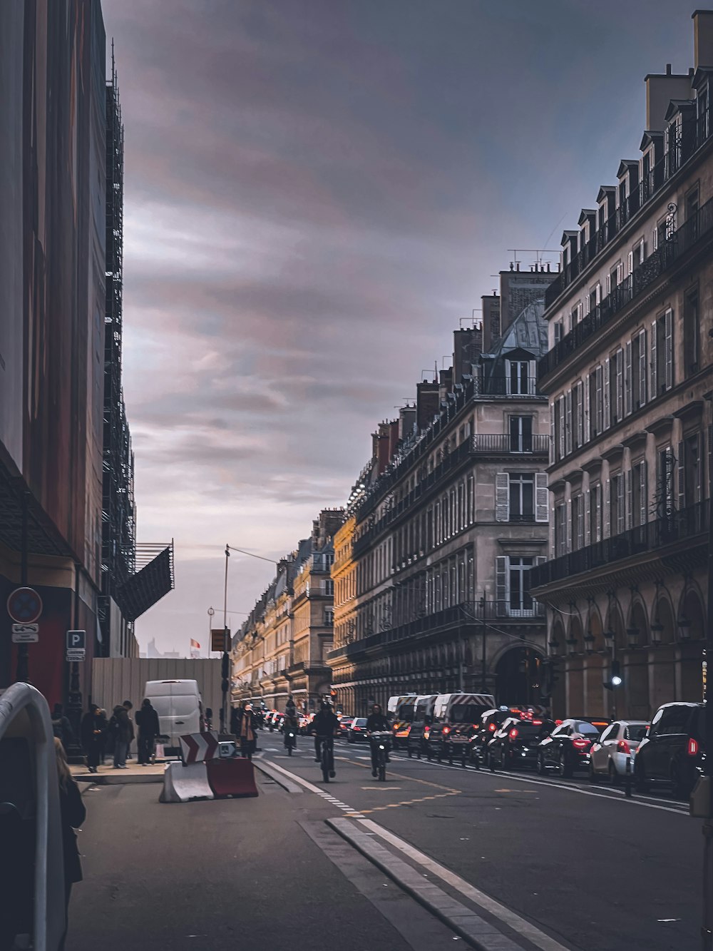 a group of people walking down a street next to tall buildings