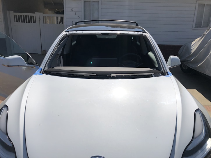 A clean car parked in a sunlit driveway.