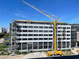 Modern residential building under construction with cranes and skilled workers in safety gear.