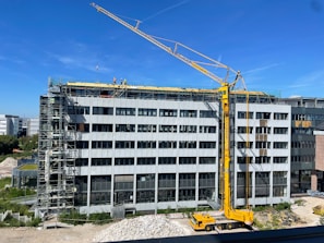 A wide-angle shot of a multi-story commercial building under construction with cranes and workers.