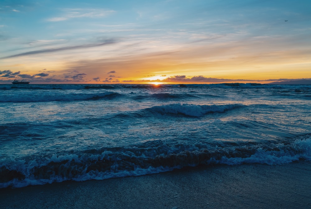 the sun is setting over the ocean waves