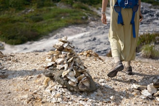 A close-up of a pilgrim's worn boots resting on a rocky path, with a walking stick beside them.