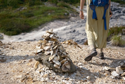 A close-up of a pilgrim's worn boots resting on a rocky path, with a walking stick beside them.