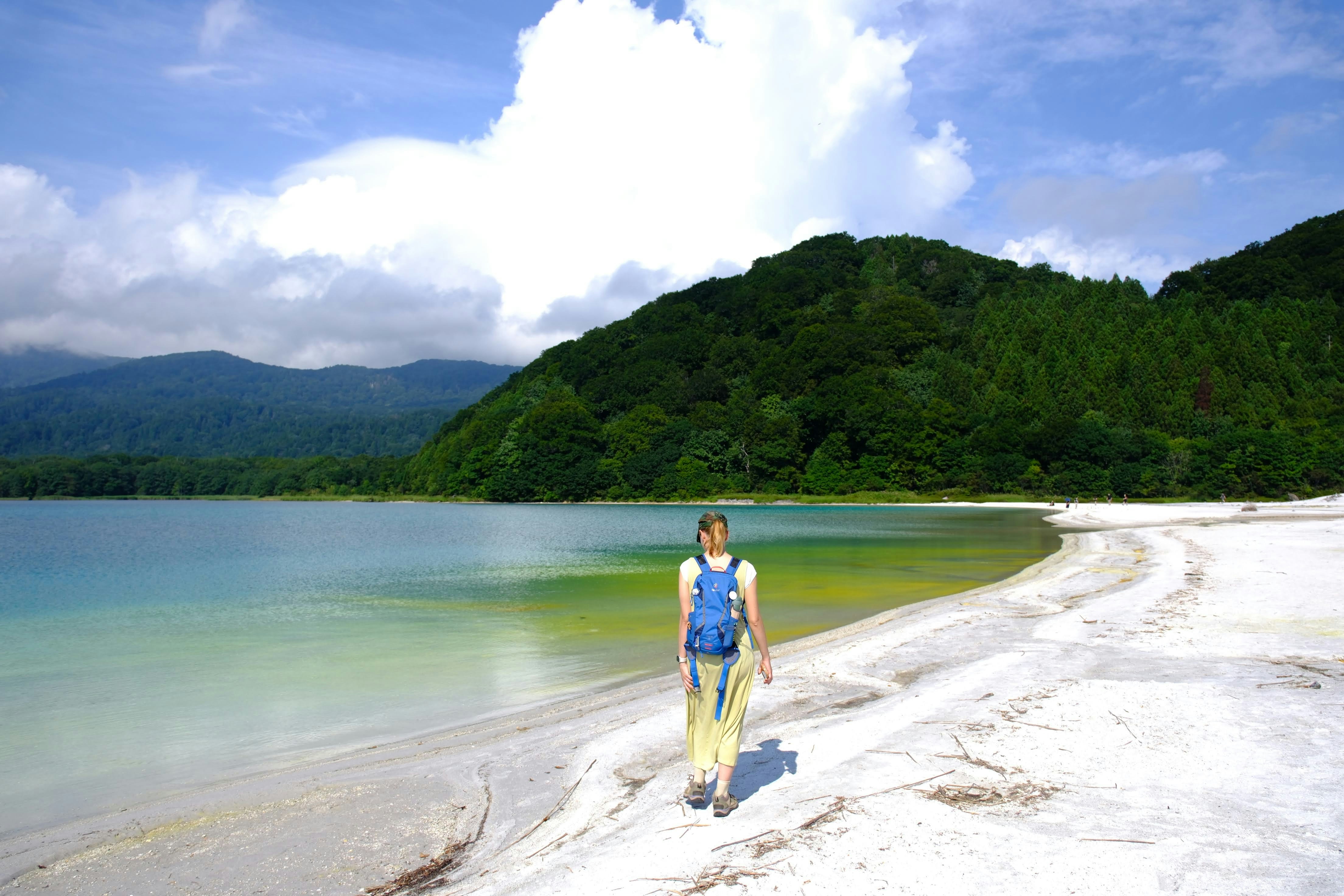 a man standing on a beach next to a body of water