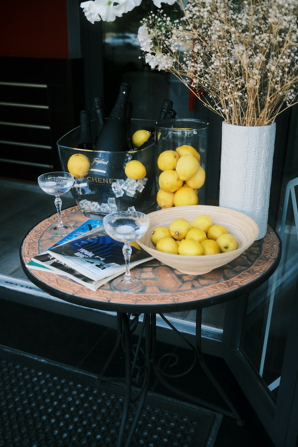 a table topped with a bowl of lemons next to a vase of flowers