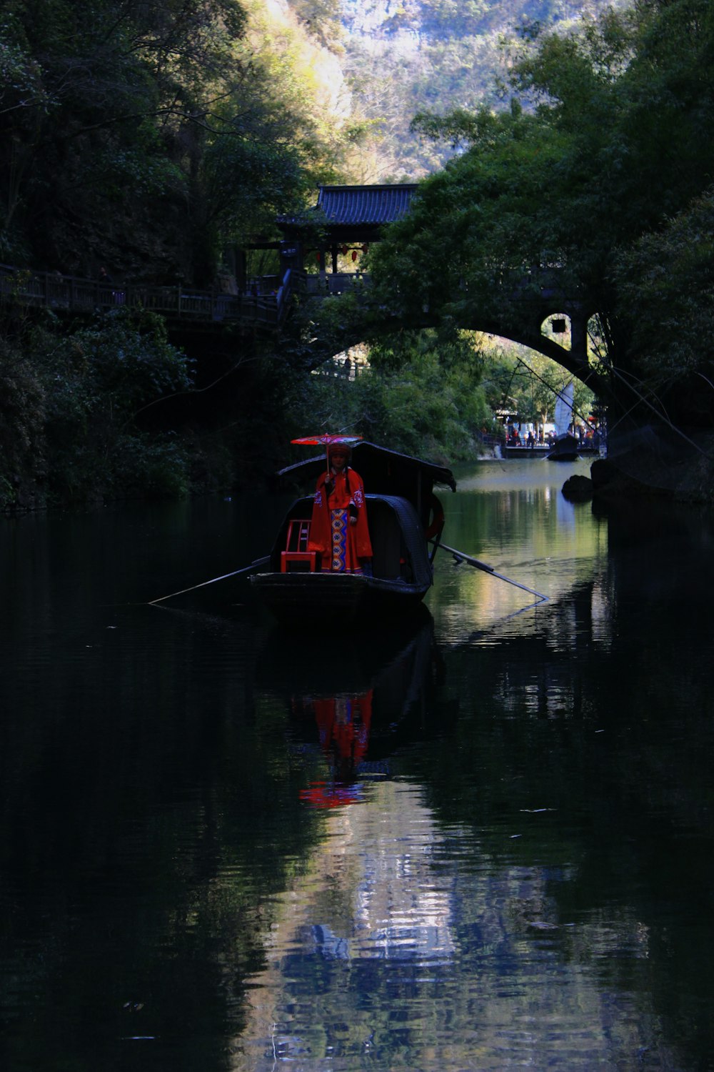 a boat floating down a river under a bridge