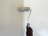 a person using a paint roller to paint a wall