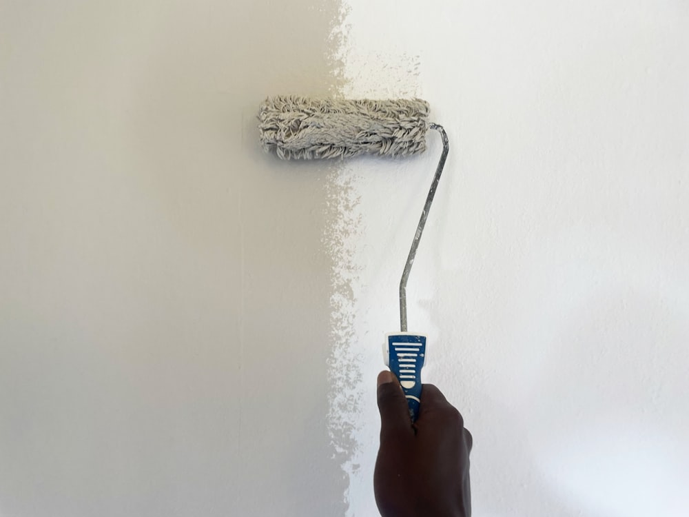 a person using a paint roller to paint a wall