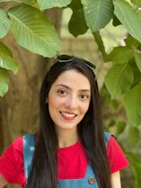 Smiling young woman wearing a vibrant Stunna Apparel hoodie outdoors on a sunny day.