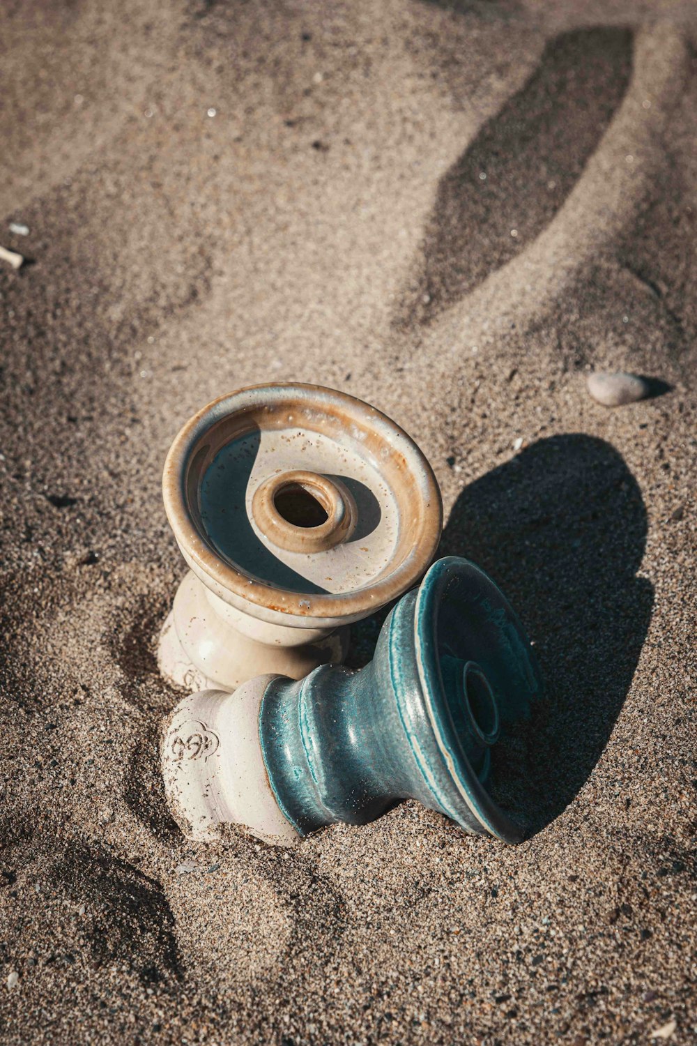 a broken vase sitting on top of a sandy beach