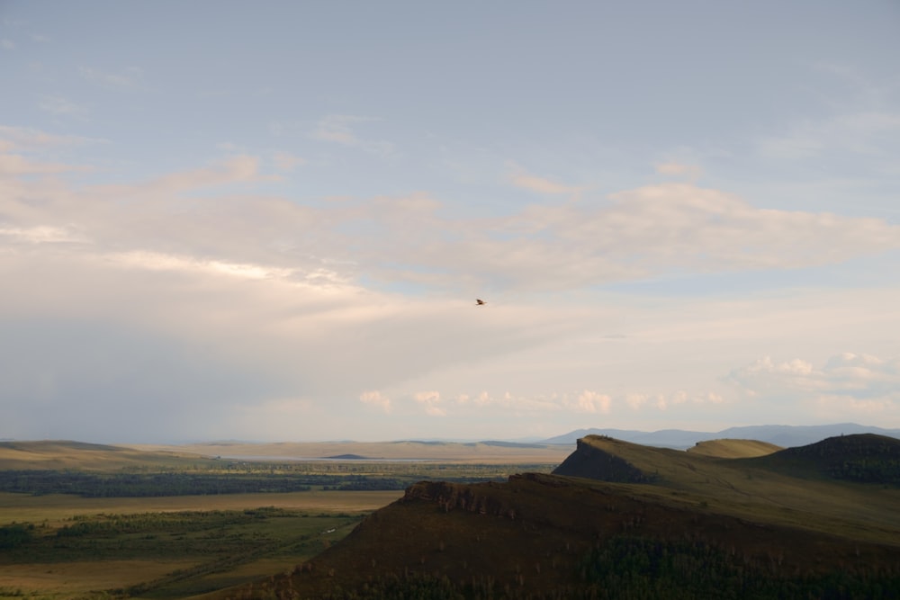 a lone bird flying over a mountain range