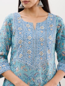Close-up of a vibrant kurti with intricate embroidery, displayed on a wooden hanger with soft natural light.
