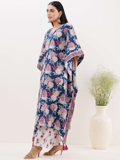 Woman wearing a bright summer dress and matching accessories standing in a sunlit room.