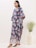A happy woman wearing a stylish dress in a bright, airy room.