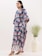 A happy woman wearing a stylish dress in a bright, airy room.