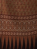 The image displays a fabric or textile with intricate patterns. The upper portion features repetitive floral motifs in red on a beige background. Below it, there is a segment with zigzag patterns in shades of brown. This is followed by a section with symmetrical, ornamental designs in beige and dark brown. The bottom-most part showcases vertical elements, resembling leaves or feathers, in red and black.