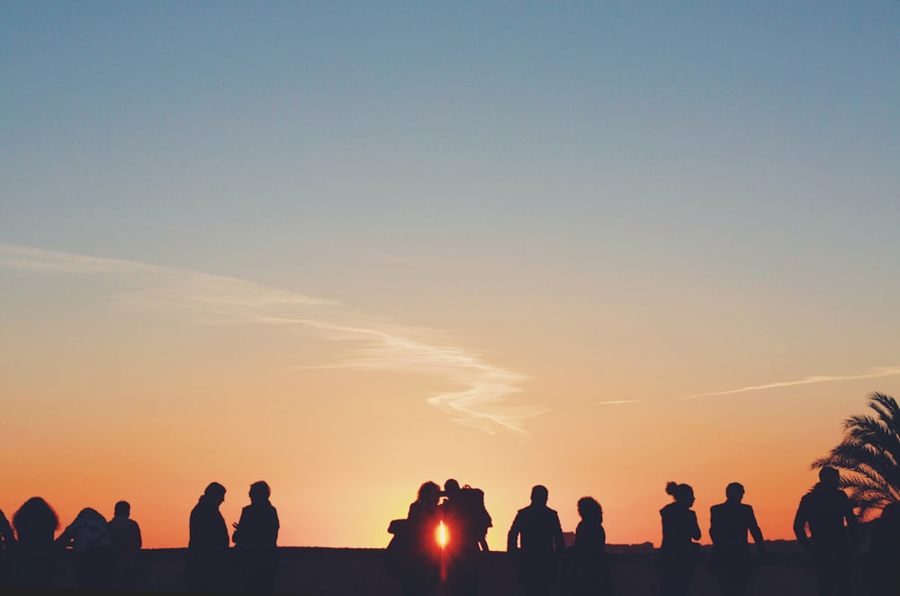 a group of people standing in front of a sunset