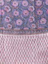 A richly patterned textile featuring elaborate floral designs with large pink flowers against a deep blue background on the upper section. The lower section showcases a repeating pattern of small, stylized pink and red motifs on a white background, resembling teardrops or leaves. The border is ornate with intricate detailing enhancing the overall design.
