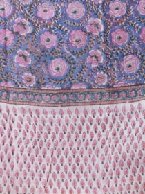 A richly patterned textile featuring elaborate floral designs with large pink flowers against a deep blue background on the upper section. The lower section showcases a repeating pattern of small, stylized pink and red motifs on a white background, resembling teardrops or leaves. The border is ornate with intricate detailing enhancing the overall design.