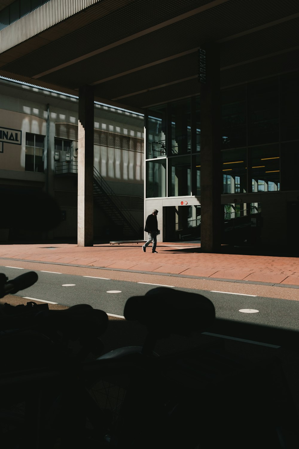 a man walking down a street next to a tall building