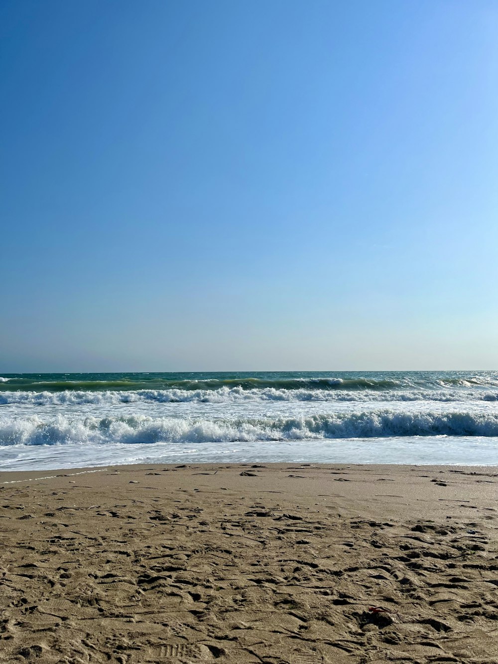 a sandy beach with waves coming in to shore