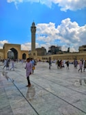 Jamaah walking peacefully in the courtyard of Masjid Nabawi under clear blue sky.