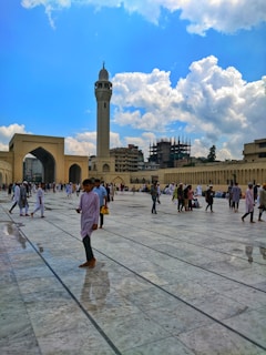 Pilgrims walking through the courtyard of the Prophet's Mosque in Madina under a clear blue sky.