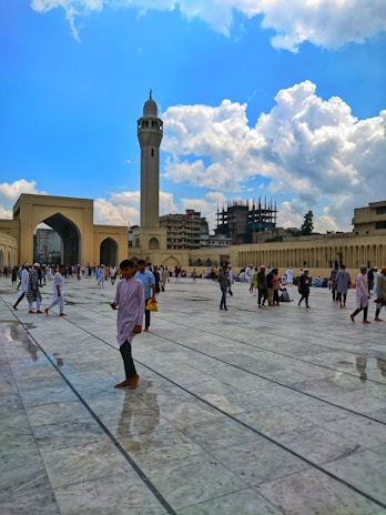 Pilgrims walking through the courtyard of the Prophet's Mosque in Madina under a clear blue sky.
