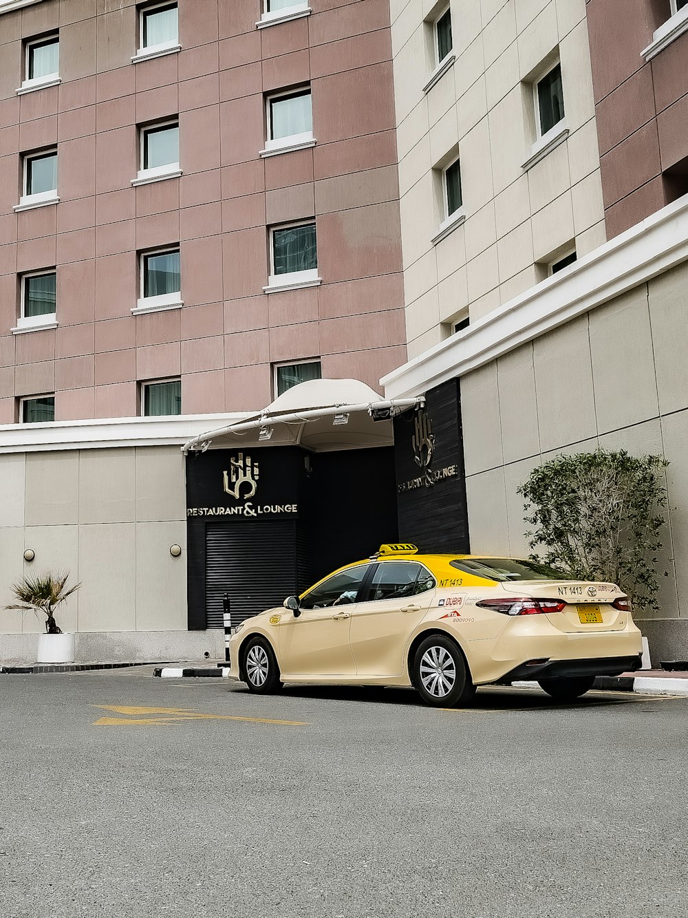 a yellow car parked in front of a hotel