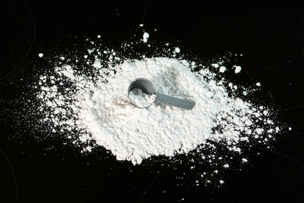 a scoop of powder next to a scoop of sugar