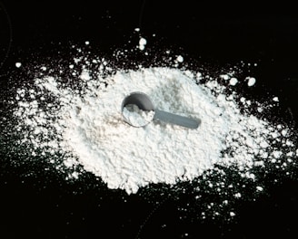 a scoop of powder next to a scoop of sugar