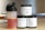 There are three supplement containers and a shaker bottle. One container is labeled 'PRE-WORKOUT' with a lightning bolt symbol, another is labeled 'CREATINE' with a chemical structure diagram, and the third is labeled 'PROTEIN' with an icon of a flexing arm. The shaker bottle contains a red liquid.