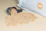 Close-up of fine dairy powder spilling from a blue and white branded sack.