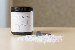 a bottle of creatine next to a spoon on a table