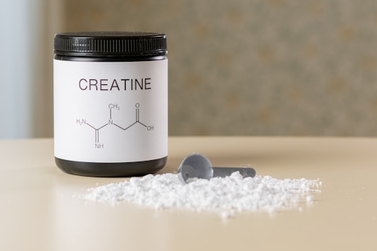 a bottle of creatine next to a spoon on a table