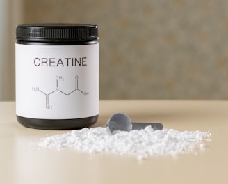 a bottle of creatine next to a spoon on a table