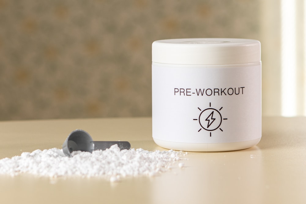 a container of pre - workout powder next to a spoon