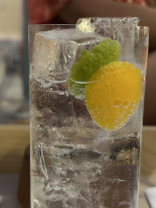 Close-up of a chilled mineral water bottle and a glass filled with lemon juice and ice.