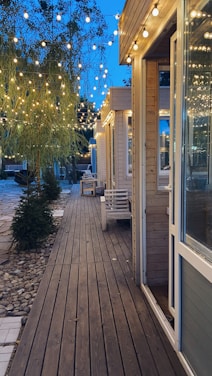 A cozy backyard setup featuring a solid wood dining set with waterproof cushions and glowing solar path lights at dusk.