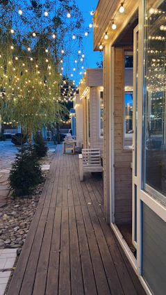 A serene twilight scene of a bespoke outdoor entertaining area featuring warm timber decking, soft glowing lights, and lush greenery.