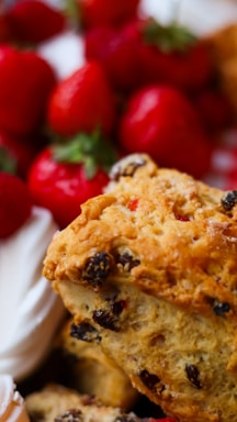 Close-up of artisan scones with clotted cream and tea on a rustic wooden table.