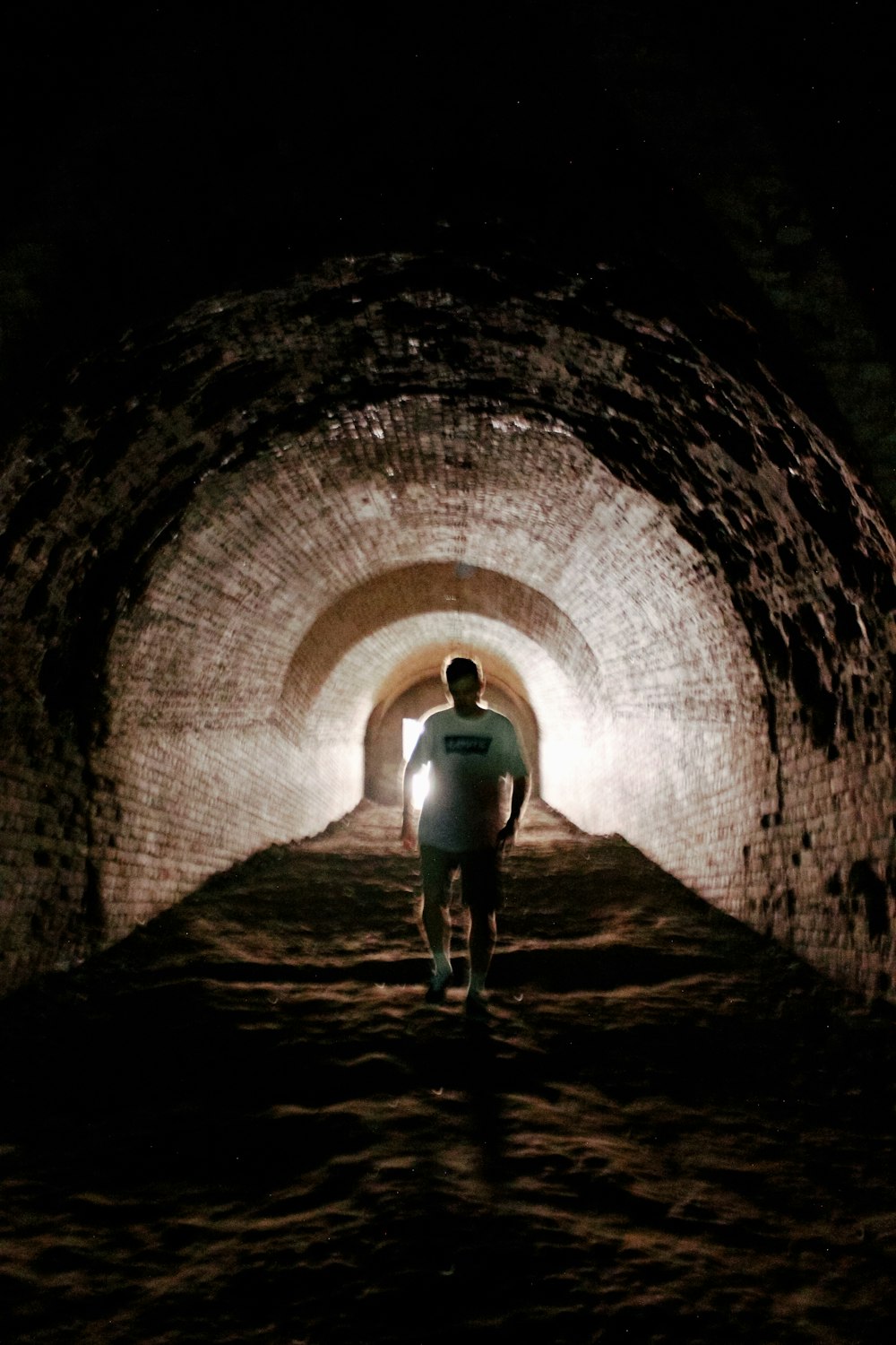 a man is walking through a dark tunnel