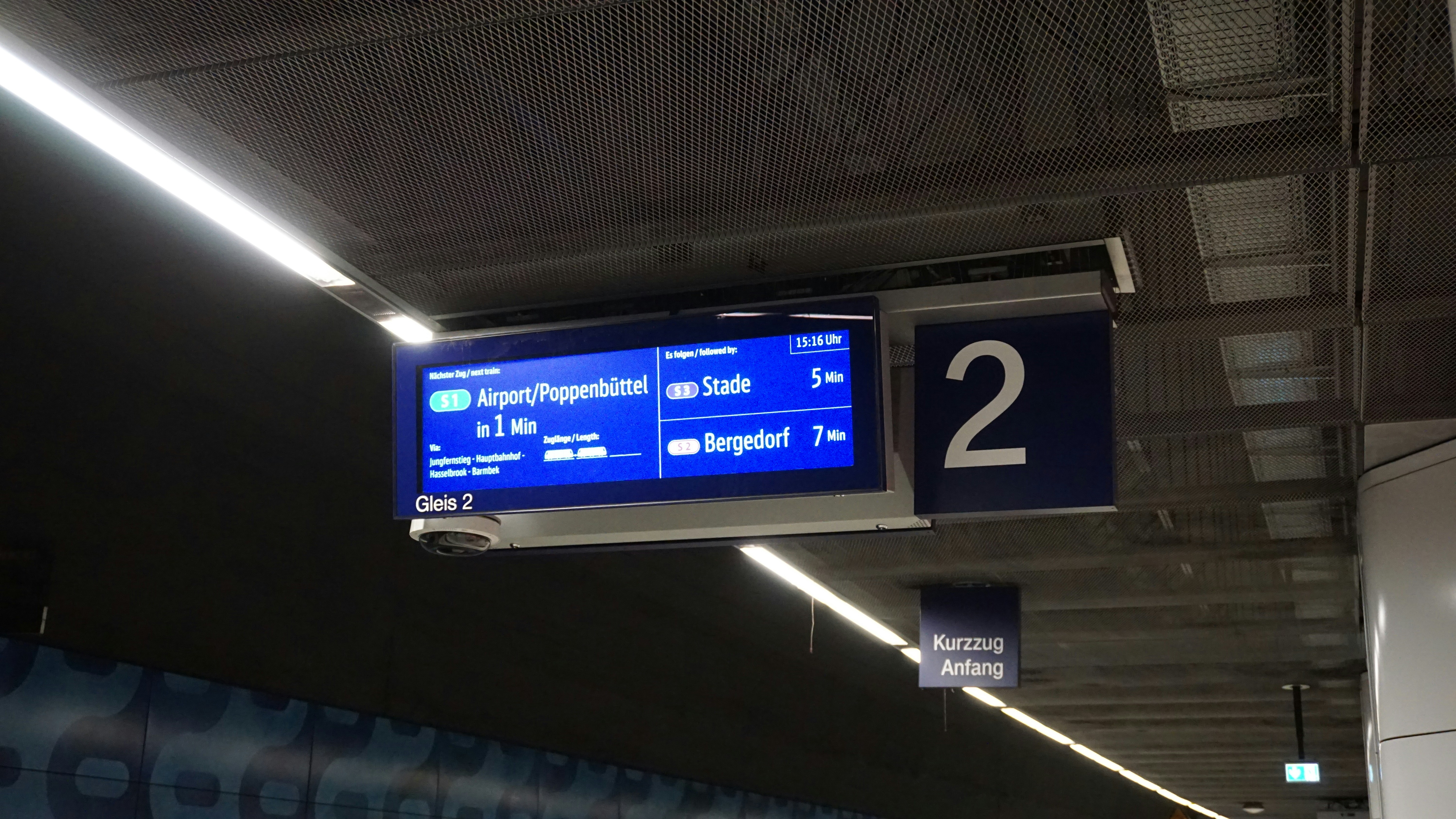 a blue sign hanging from the ceiling of a train station