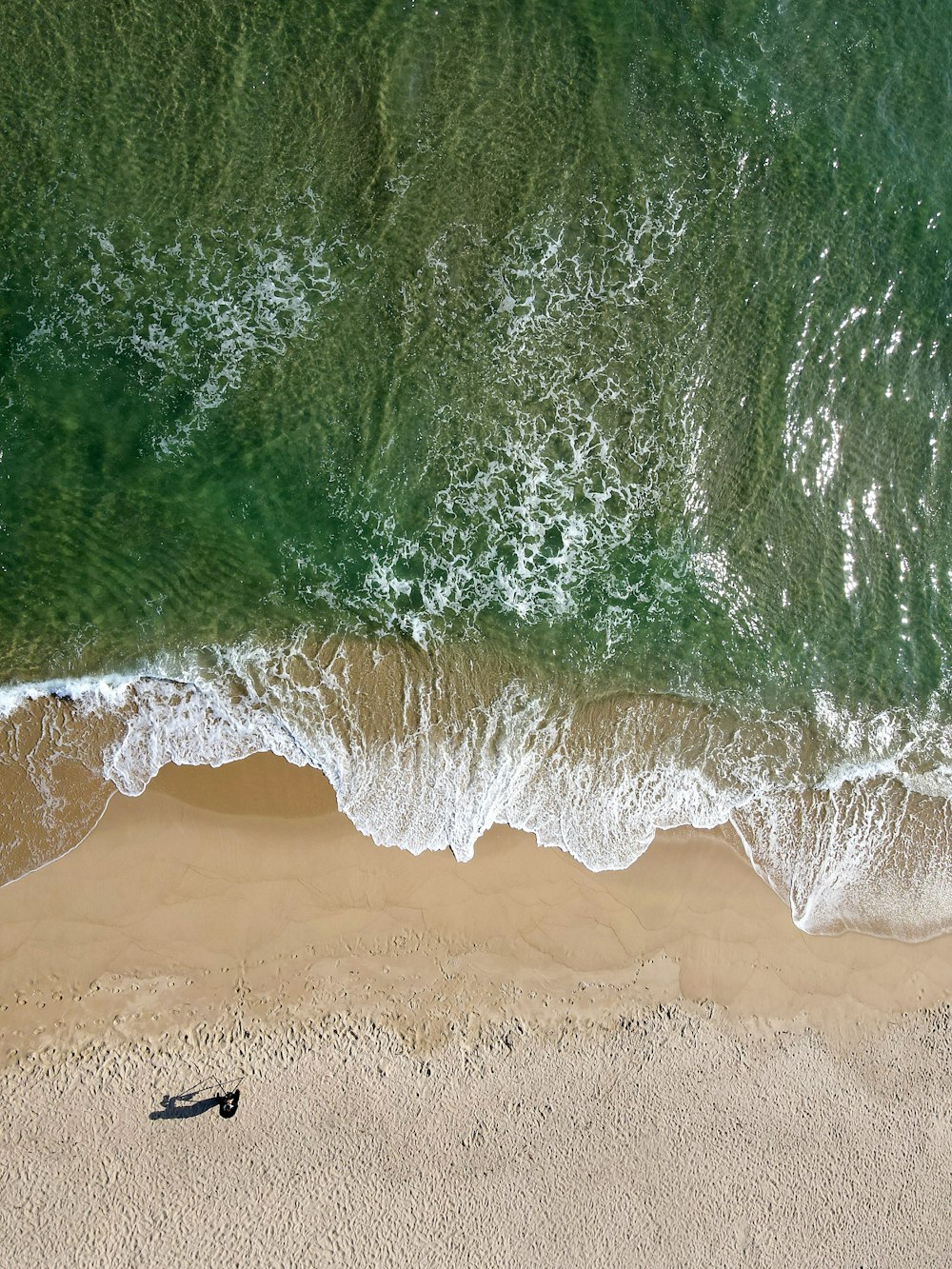 an aerial view of a beach with a boat in the water