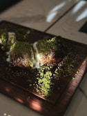 a wooden cutting board topped with meat covered in green stuff