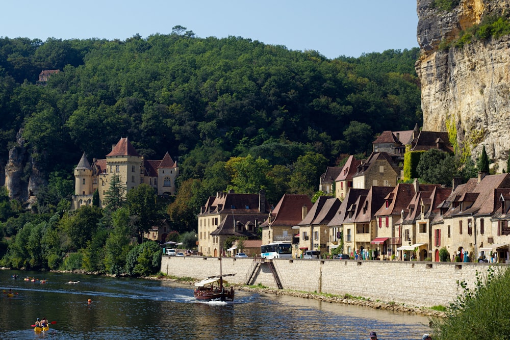 a small boat is on the river near a village