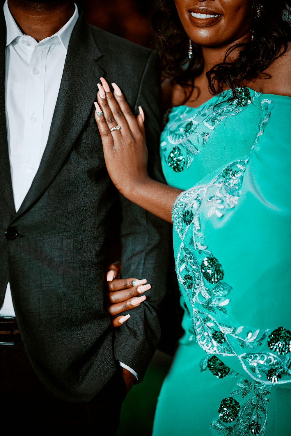 a woman in a green dress standing next to a man in a suit