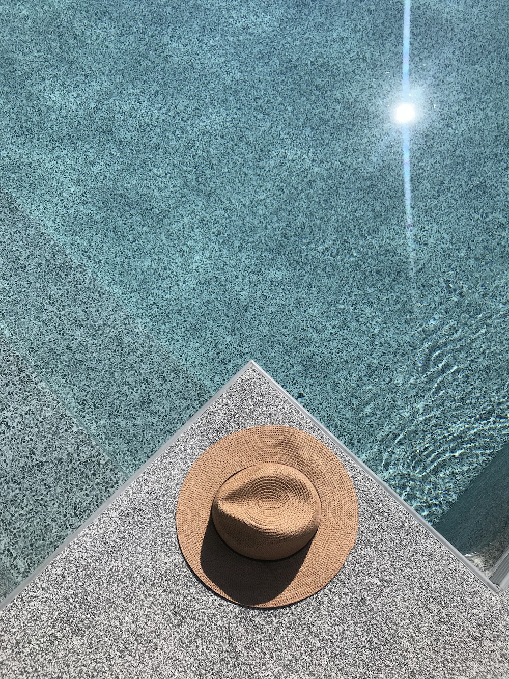 a hat sitting on the edge of a swimming pool