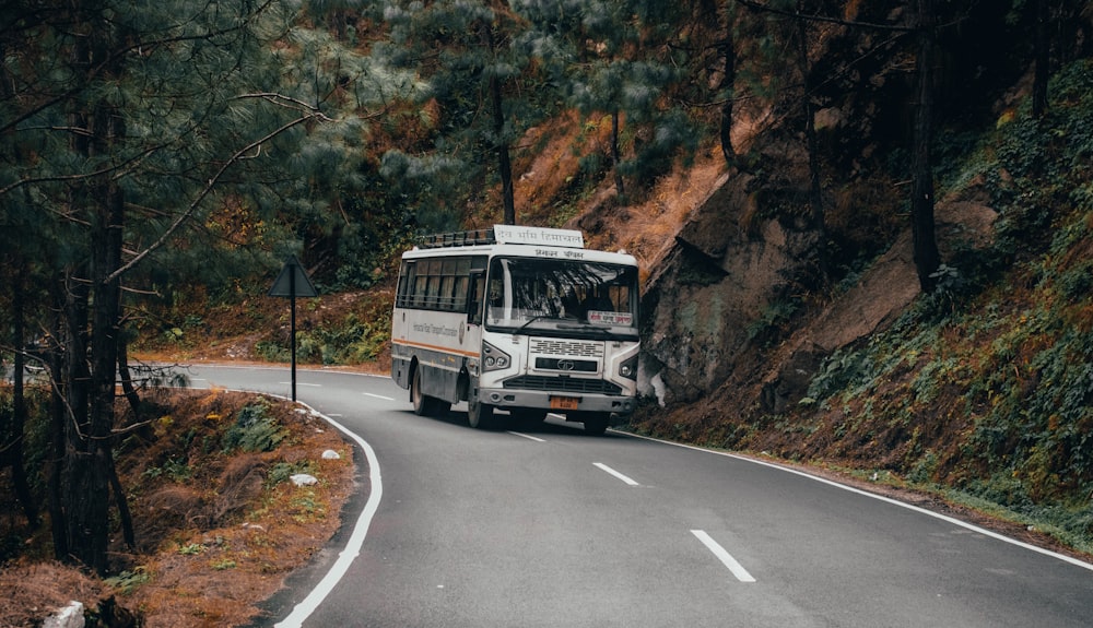 a white bus driving down a curvy road